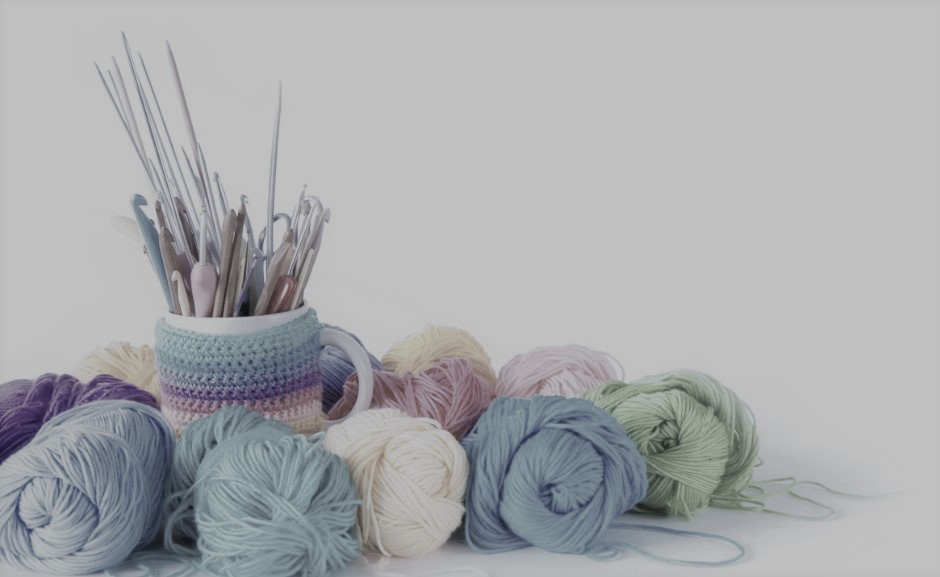 Yarn with a bowl of knitting needles and crochet hooks.